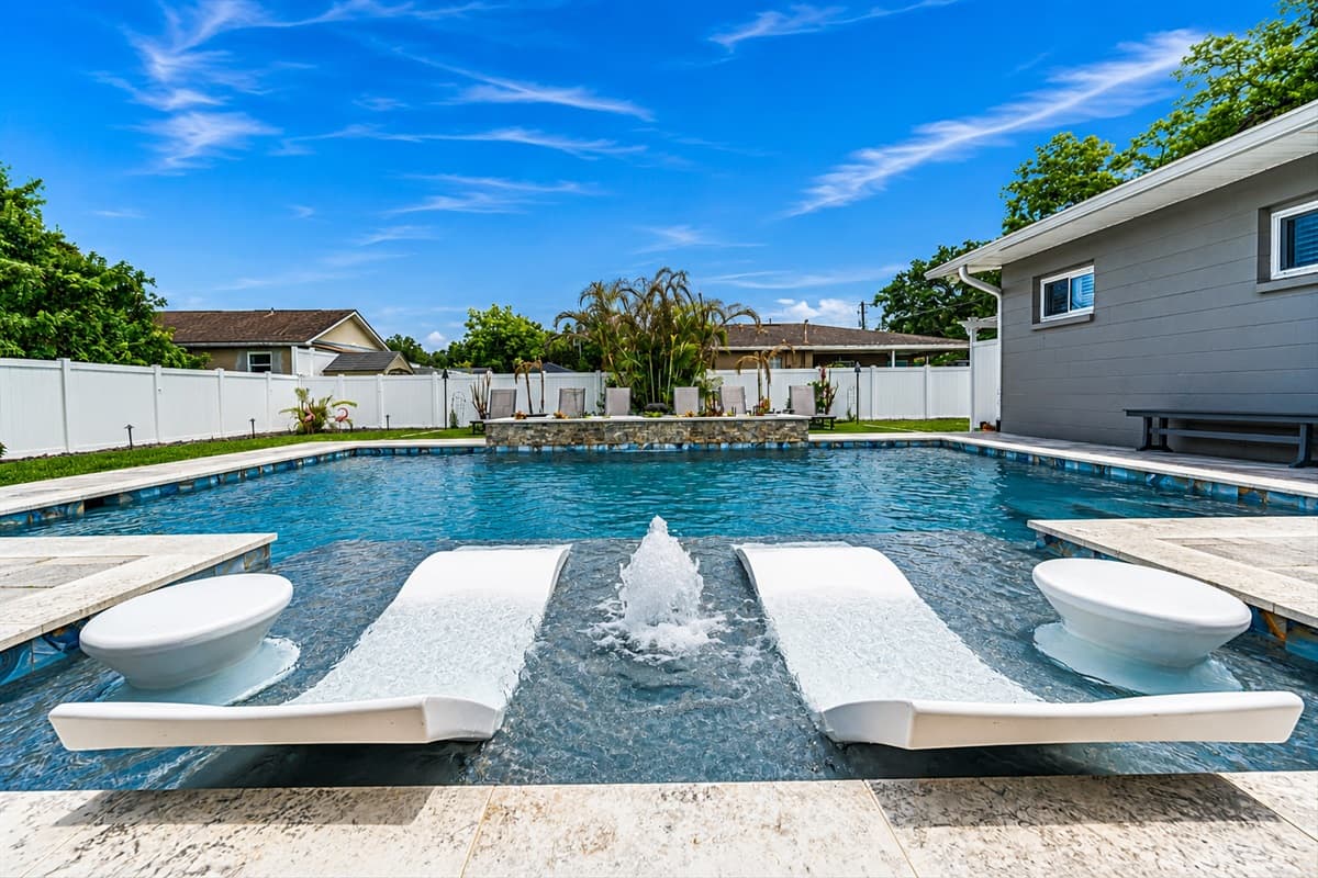 Luxurious tanning ledge with in-pool loungers and water features creating the perfect relaxing retreat.