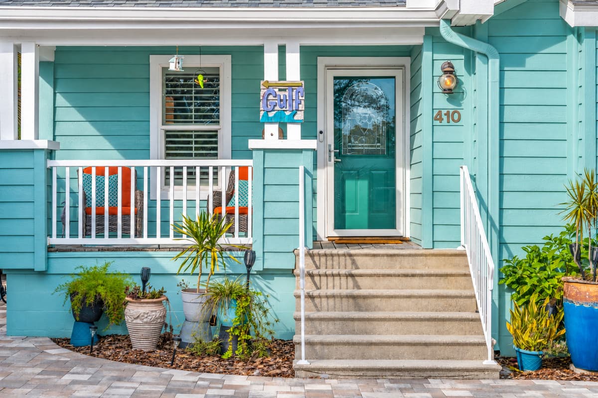 Charming curb appeal includes a welcoming porch, vibrant potted plants, and refreshing coastal architecture.