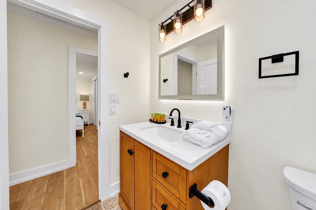 Warm wood vanity, bright lighting. Bathroom 2 has a lighted mirror and wood vanity with fresh towels waiting. Small details that make mornings easier.