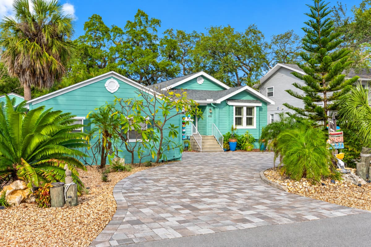 A welcoming cottage façade with fresh coastal colors, stylish white trim, and a spacious paver driveway.