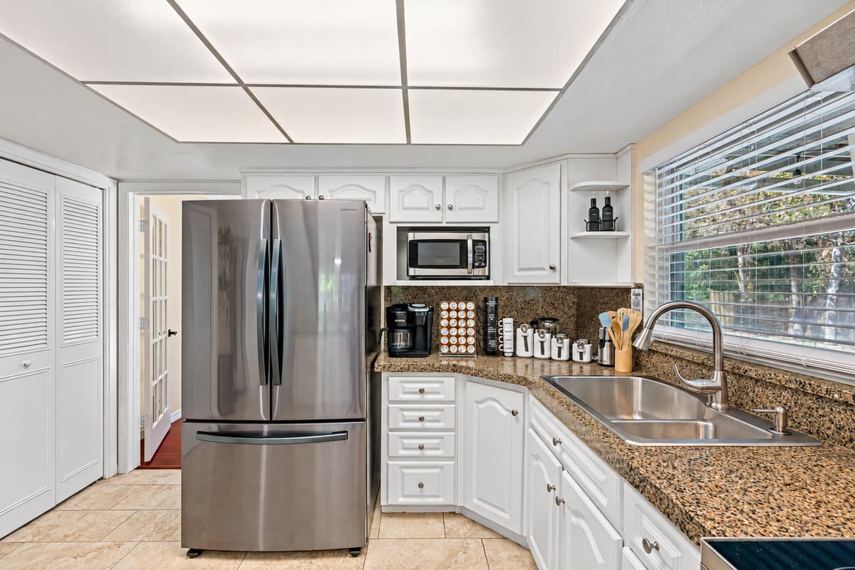 A kitchen that exudes timeless elegance! You'll be captivated by the crisp, clean lines of the white painted cabinets that provide a stunning contrast against rich, natural wood flooring.