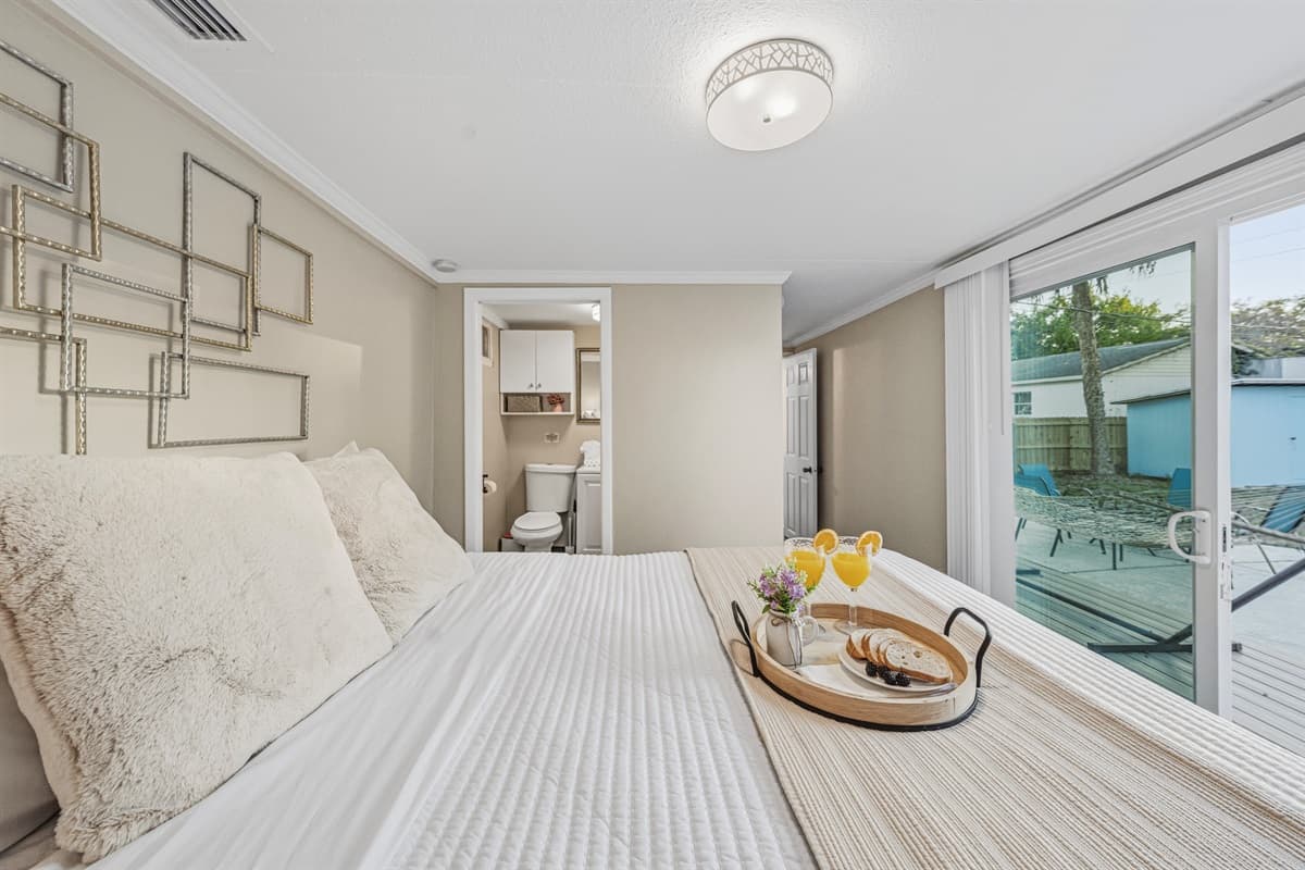 Master bedroom with plush bedding and direct access to the backyard.