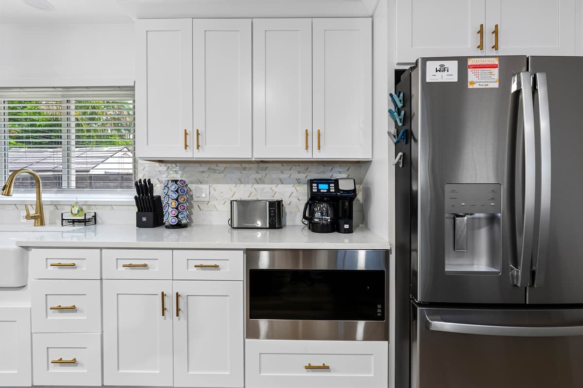 Crisp white cabinets, gold hardware, and quartz counters give this kitchen timeless elegance.