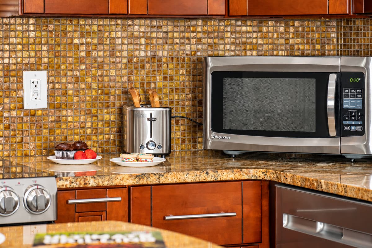 A golden mosaic backsplash brings texture and sparkle to the space, tying together the cabinetry and granite countertops.