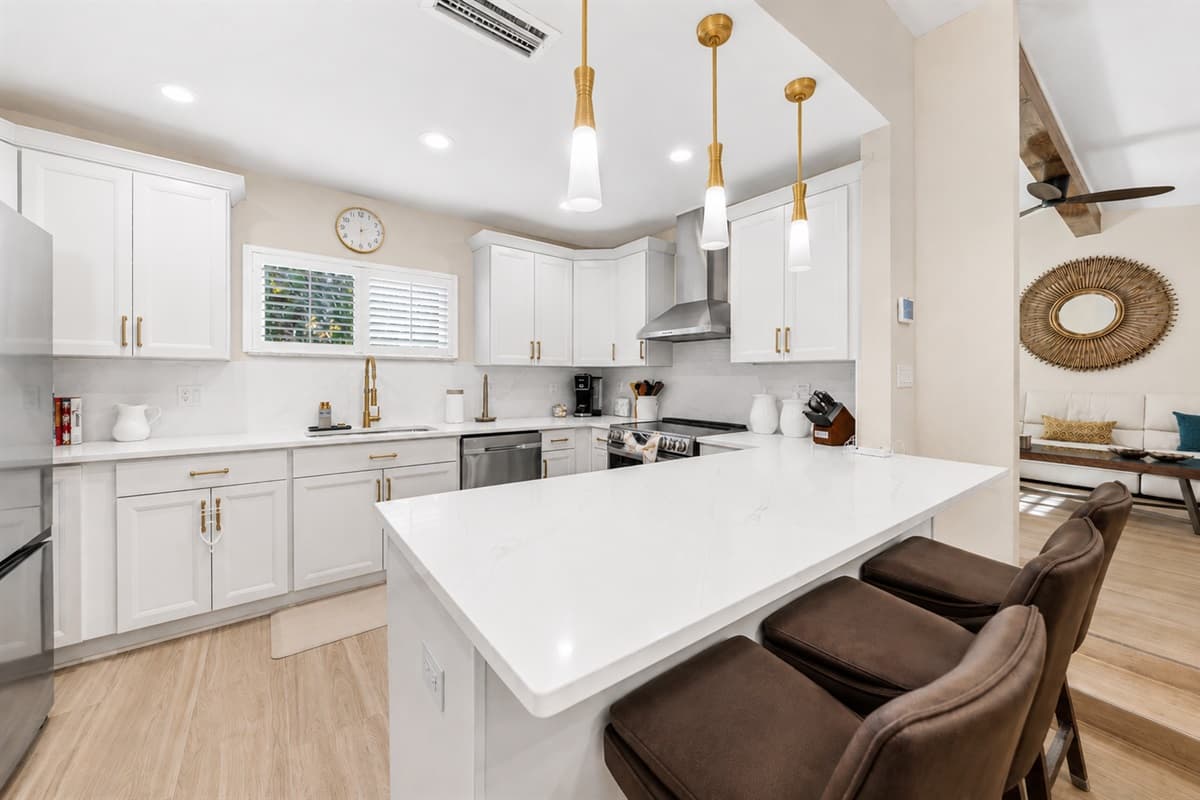 Bright and modern fully equipped kitchen featuring quartz countertops, stainless steel appliances, and oversized island seating.
