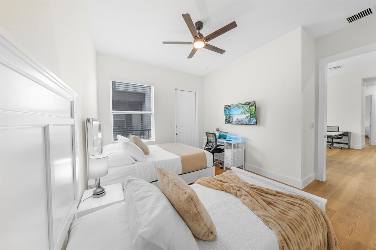 Bedroom with two beds, TV, and workspace—perfect for relaxing or working.
