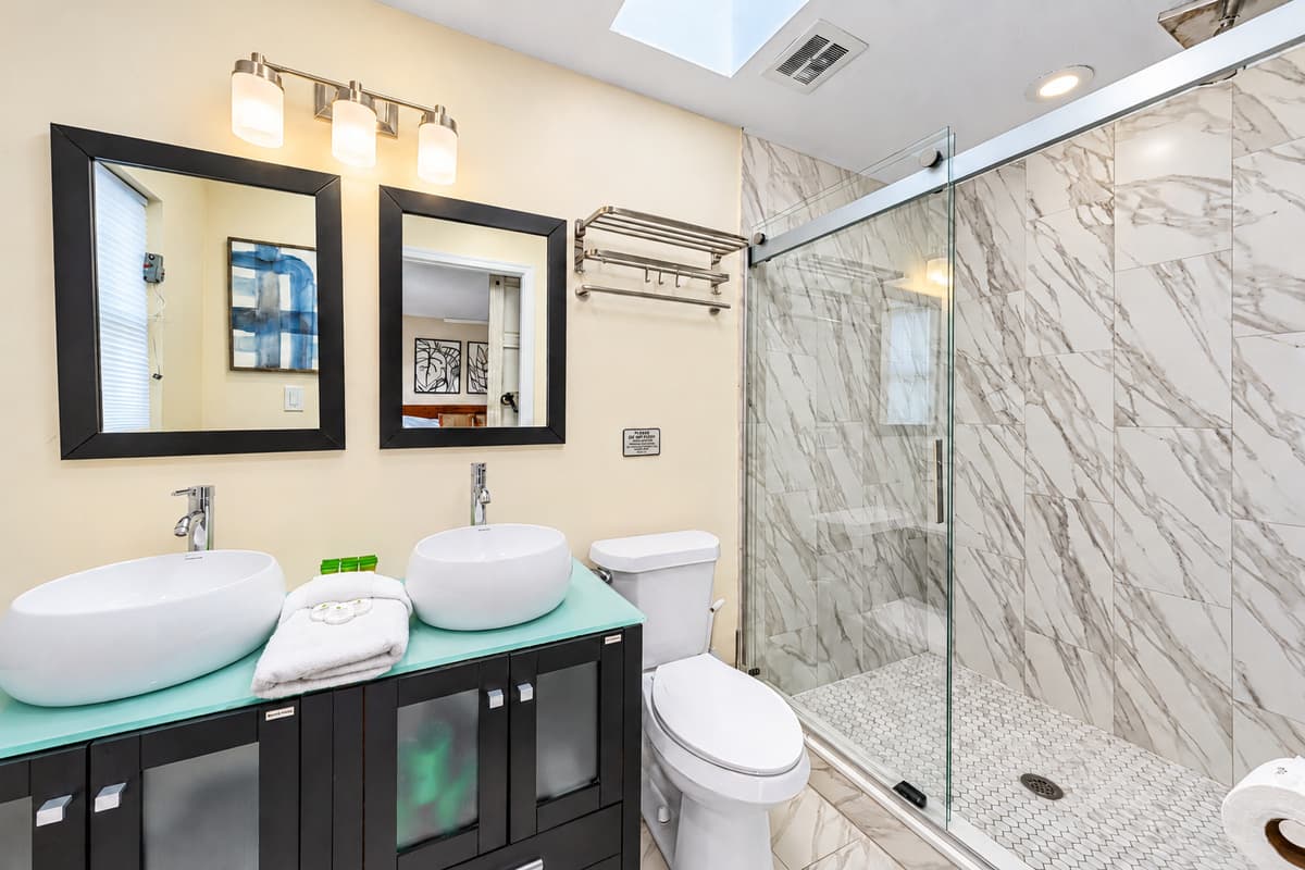 Modern bathroom with dual vessel sinks and a luxurious walk-in marble shower.