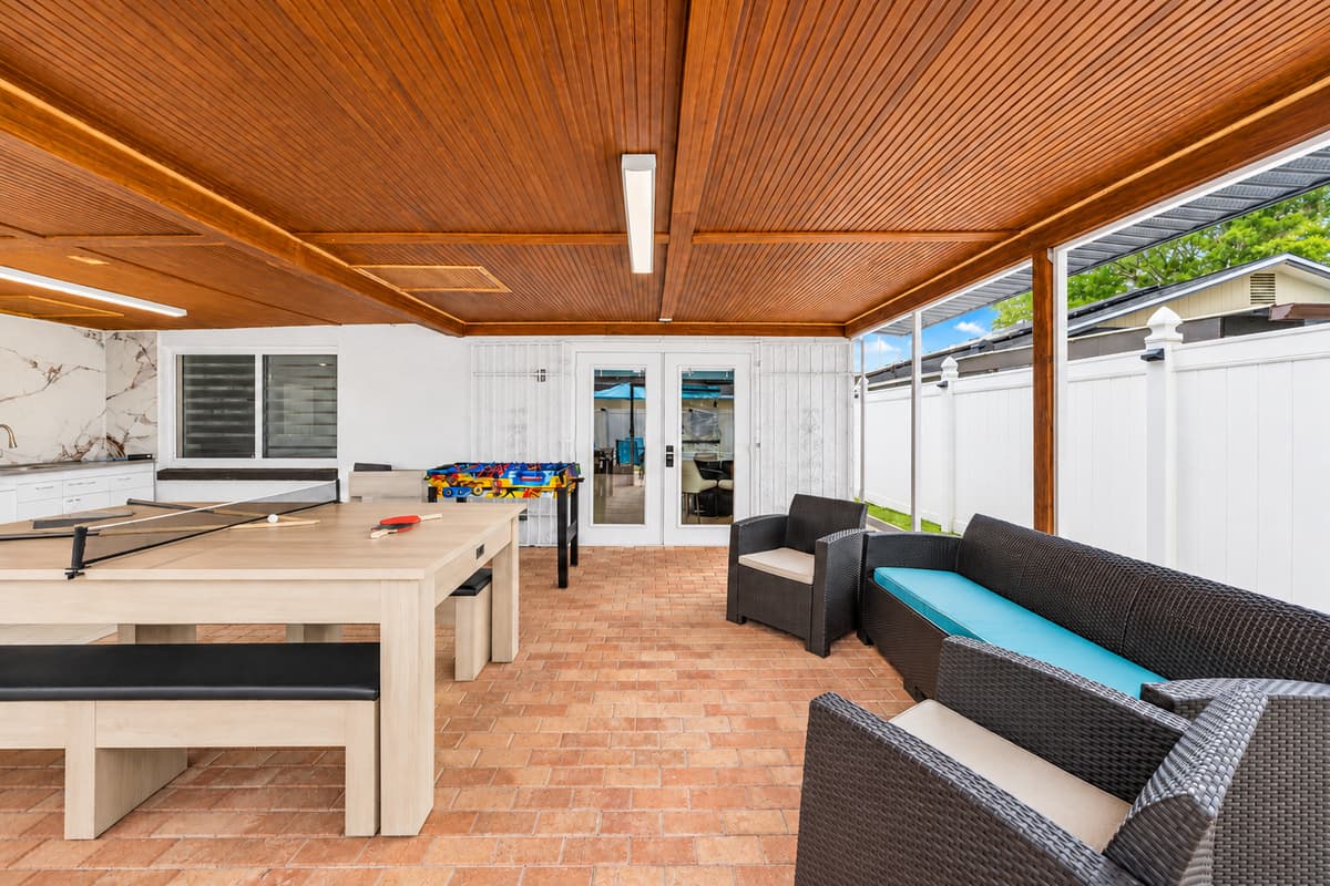 Relax and unwind in the spacious covered outdoor living area, complete with lounge seating, games, and plenty of space for making memories with family and friends.