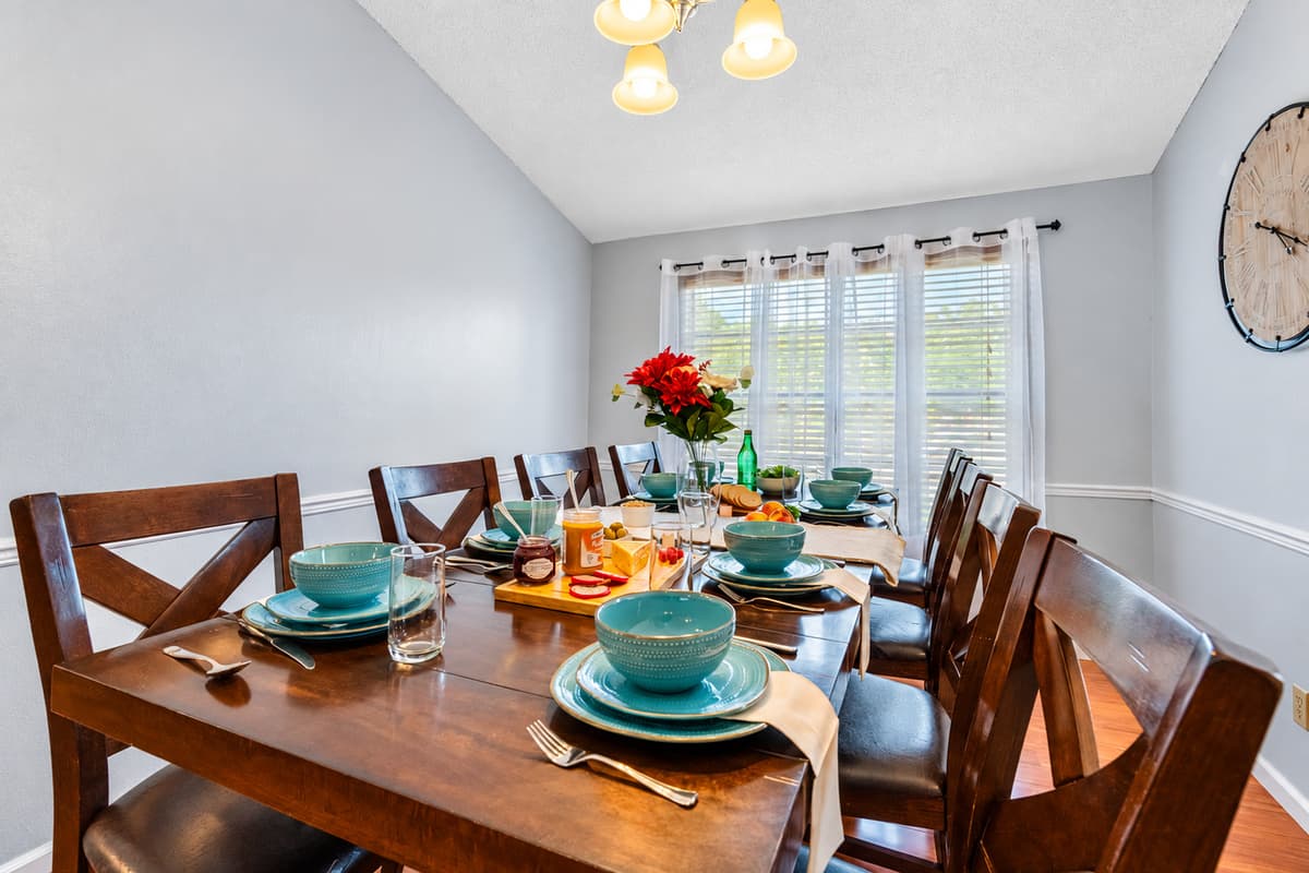 Enjoy meals together at this thoughtfully arranged dining table, complete with elegant settings and a centerpiece that adds a pop of color.