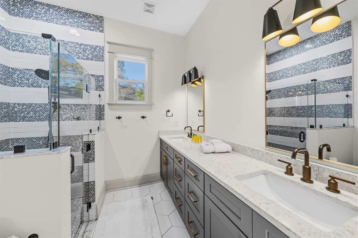 Spa-worthy master bath in this brand-new home! Bold blue and white mosaic tile shower, sleek navy double vanity with gold fixtures, and a skylight overhead — luxury you won't find in older Tampa properties.