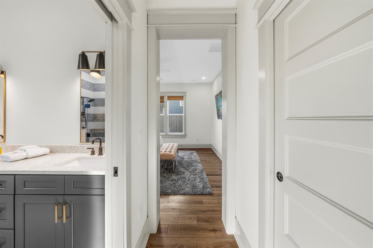 Sophisticated hallway with elegant white shiplap wall paneling, a statement mirror, rich hardwood floors, and sleek charcoal cabinetry. Every inch of this brand-new Seminole Heights home has been thoughtfully designed.