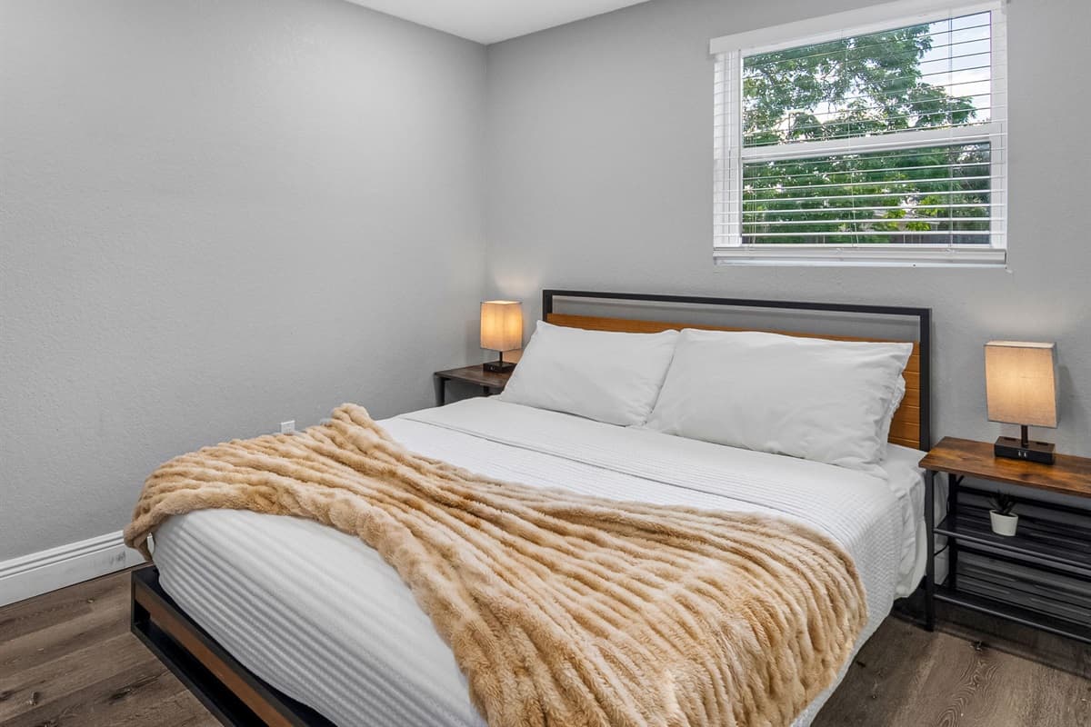 A warm and welcoming bedroom featuring a soft bed, mirrored closet, and soothing neutral tones.