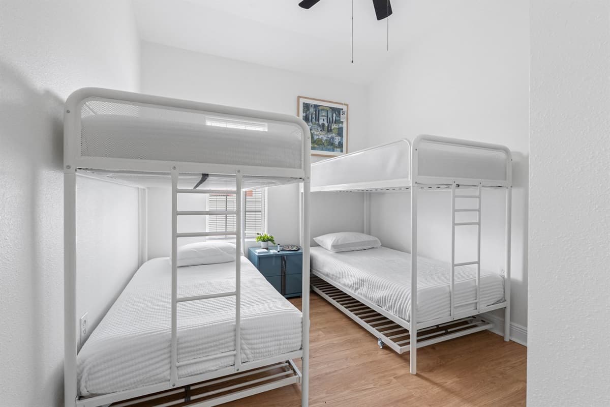 This cheerful bunk bedroom provides flexible sleeping arrangements with two twin bunk beds, crisp white linens, and a cozy layout designed for both comfort and functionality.