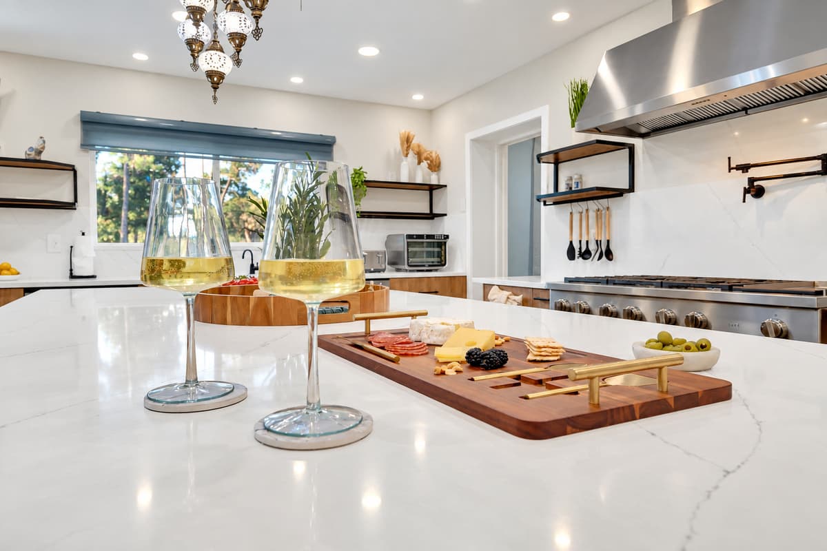 Pour two glasses and let dinner take three hours. Charcuterie on the island, wine poured, the professional range behind — the evening that starts in the kitchen and never leaves.