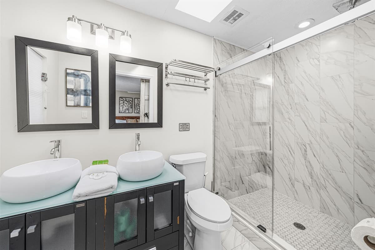 Modern bathroom with dual vessel sinks and a luxurious walk-in marble shower.