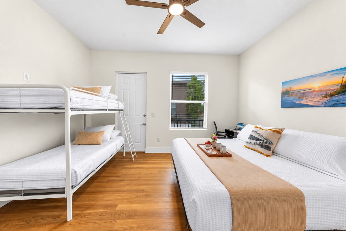 Bunk beds kids love, a king parents need. Bedroom 3 pairs a king bed with a bunk bed, a beach-sunset print, and a ceiling fan. The kids get their adventure, the adults get a real night's sleep. No compromise required.
