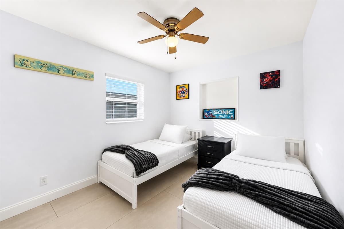 Comfortable twin bedroom with modern furnishings, ceiling fan, and cheerful artwork.