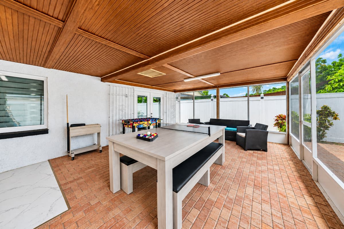 Expansive covered patio designed for entertainment, featuring a pool table, comfortable seating, and plenty of room to gather.