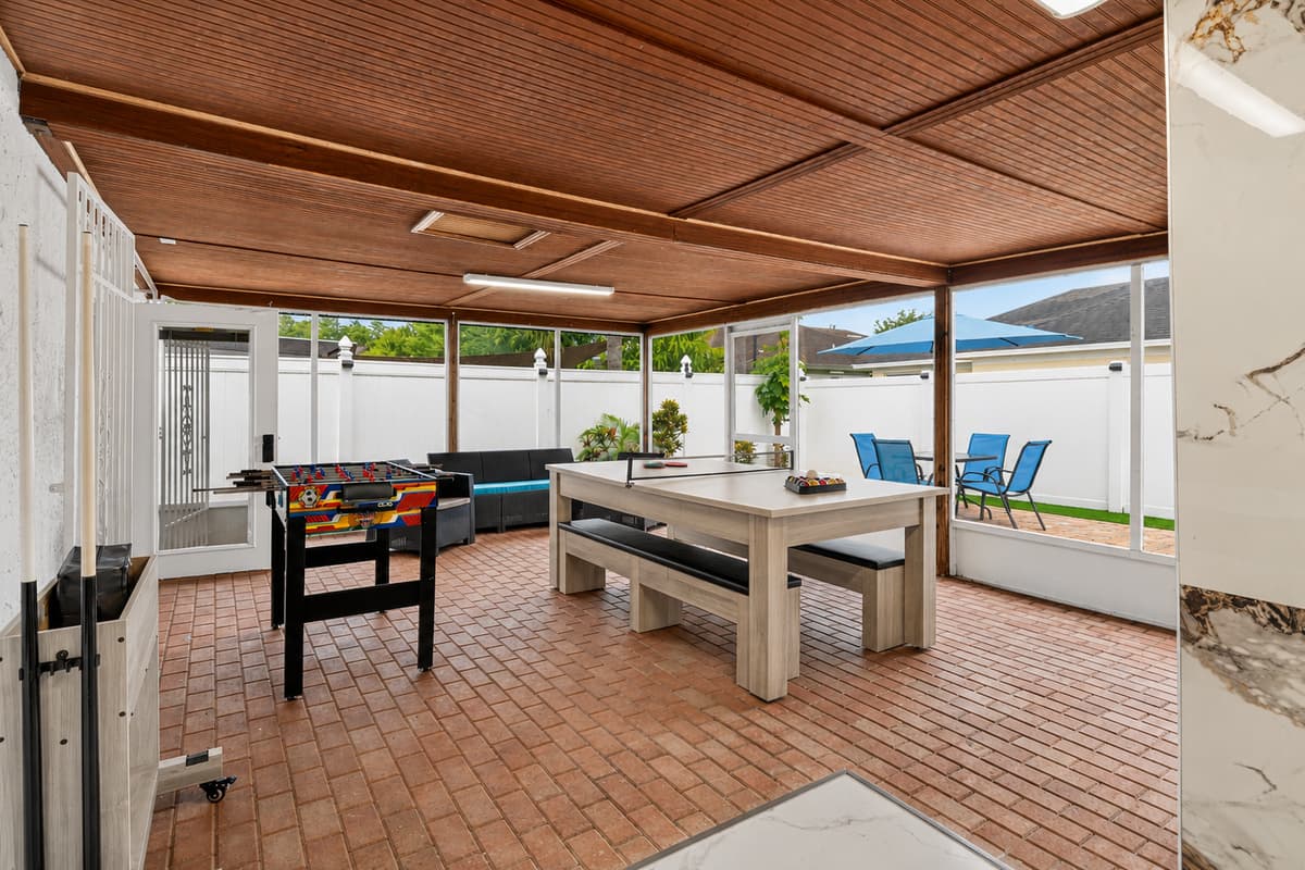 Outdoor entertainment oasis with pool table, foosball table, lounge seating, and direct access to the private pool area.