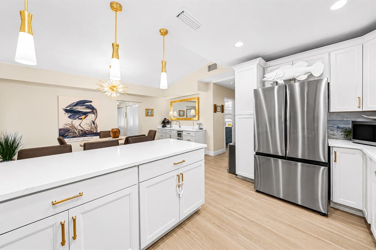 Bright open-concept kitchen featuring stainless steel appliances, quartz countertops, and elegant pendant lighting.
