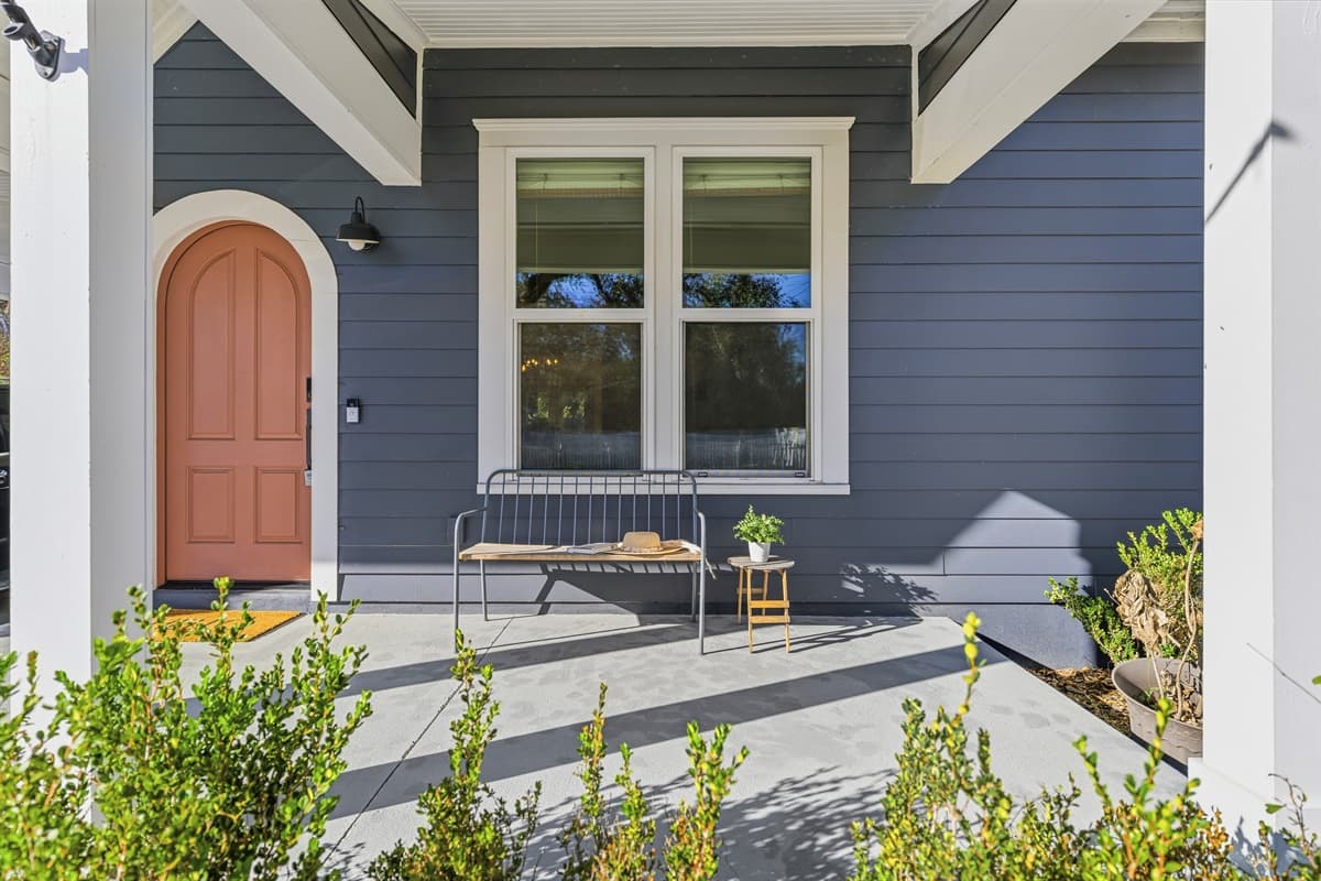 That door! The arched cognac-colored front door paired with charcoal board-and-batten siding and a sleek black sconce lantern — brand-new construction with serious style in the heart of Seminole Heights.