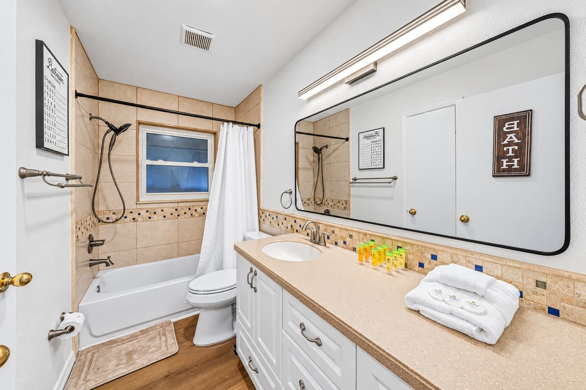 Full bathroom featuring a combination tub/shower, spacious vanity, and essential amenities 