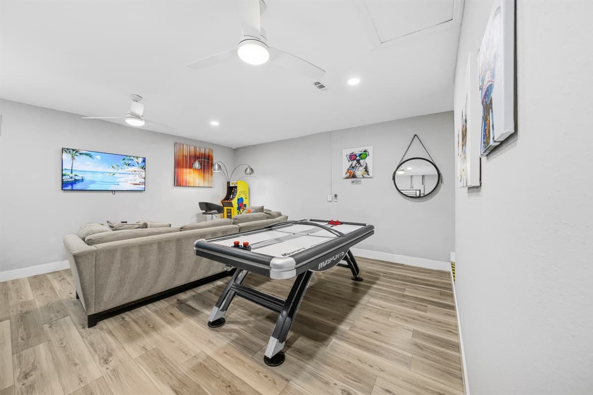 Open-concept game room with Smart TV, air hockey table, and plenty of seating.