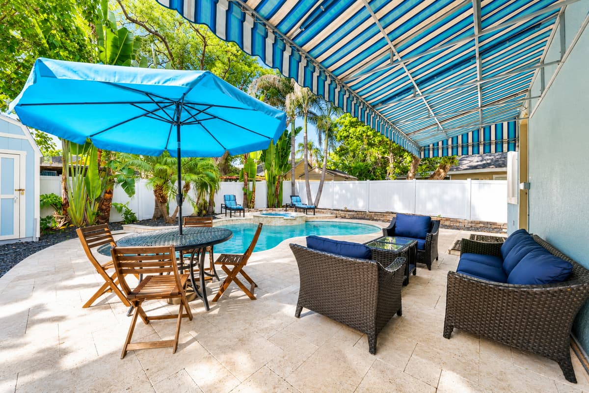 Enjoy outdoor dining and lounge seating under the shaded patio, perfect for relaxing by the pool.