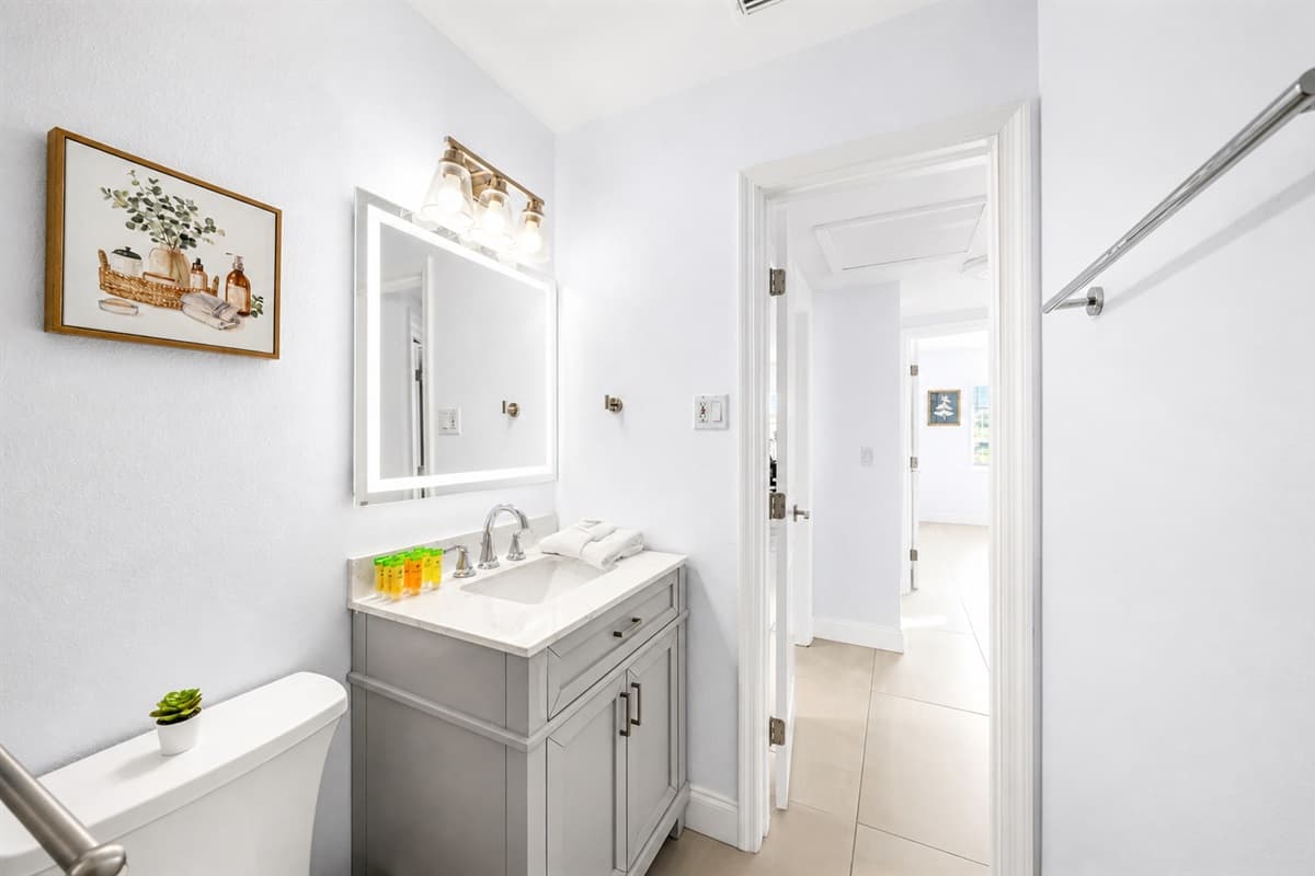 Bathroom 2 featuring a modern vanity, fresh décor, and hallway access.