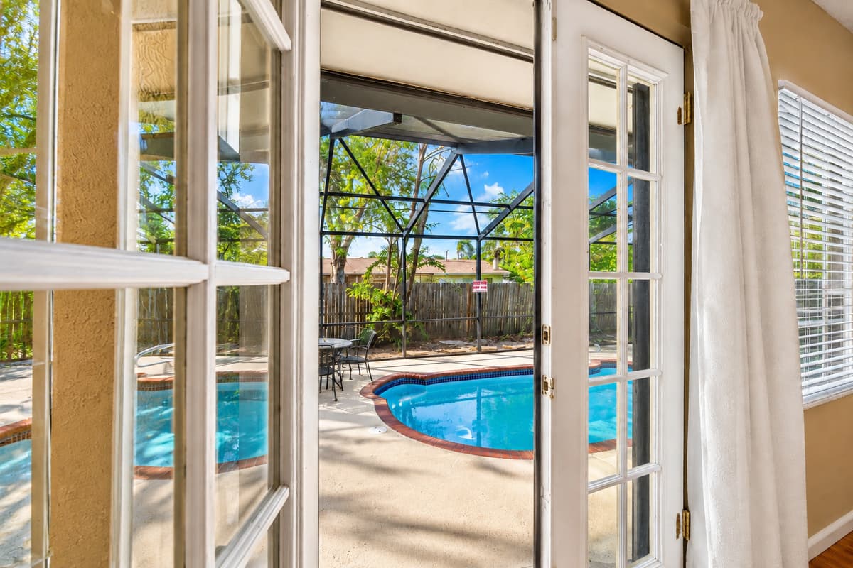 Bright interior view with French doors leading directly to the screened pool and patio area.