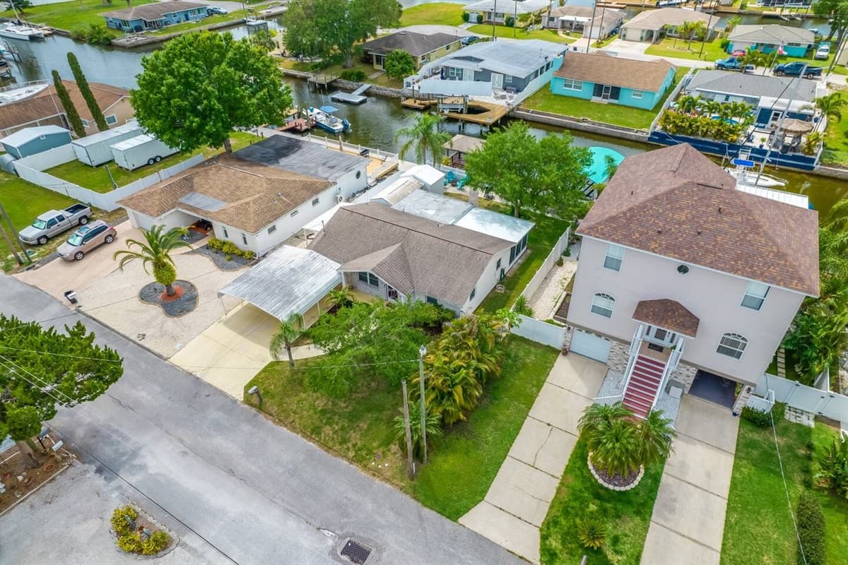 Aerial front view of our stunning property showcasing our spacious driveway and parking. The property is surrounded by trees and is fully fenced. If you are interested in this property, send us an inquiry now!