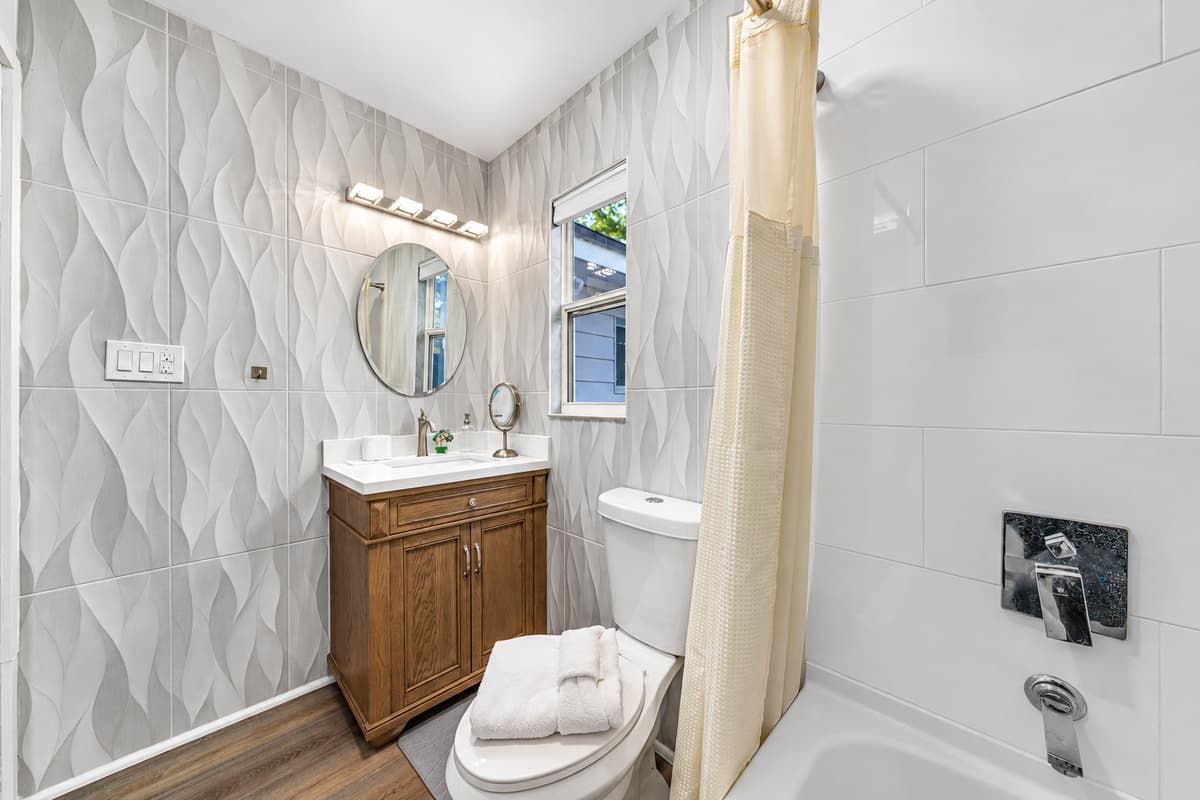 The bathroom offers a clean and refreshing space, complete with modern tile accents and a well-appointed vanity.