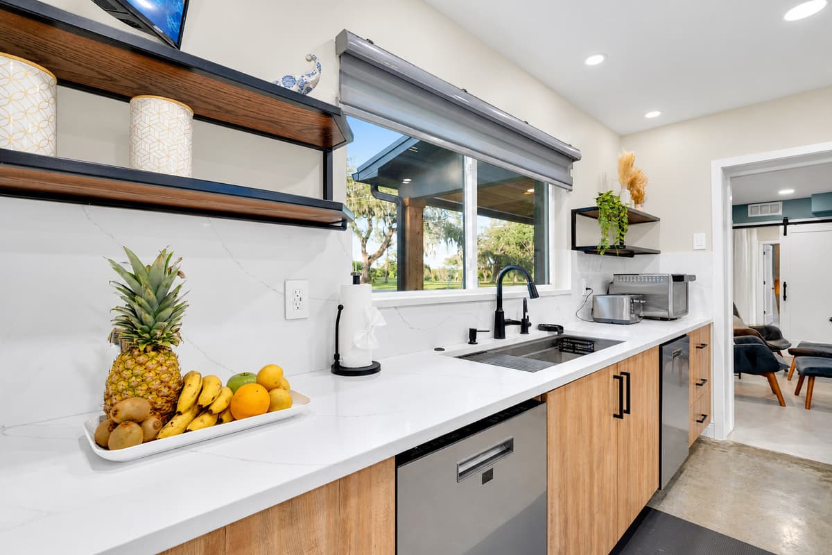 Fresh fruit, morning light, coffee already brewing. Wide counters, dishwasher and a window over the sink — the corner of the kitchen where the day quietly starts before anyone else appears.