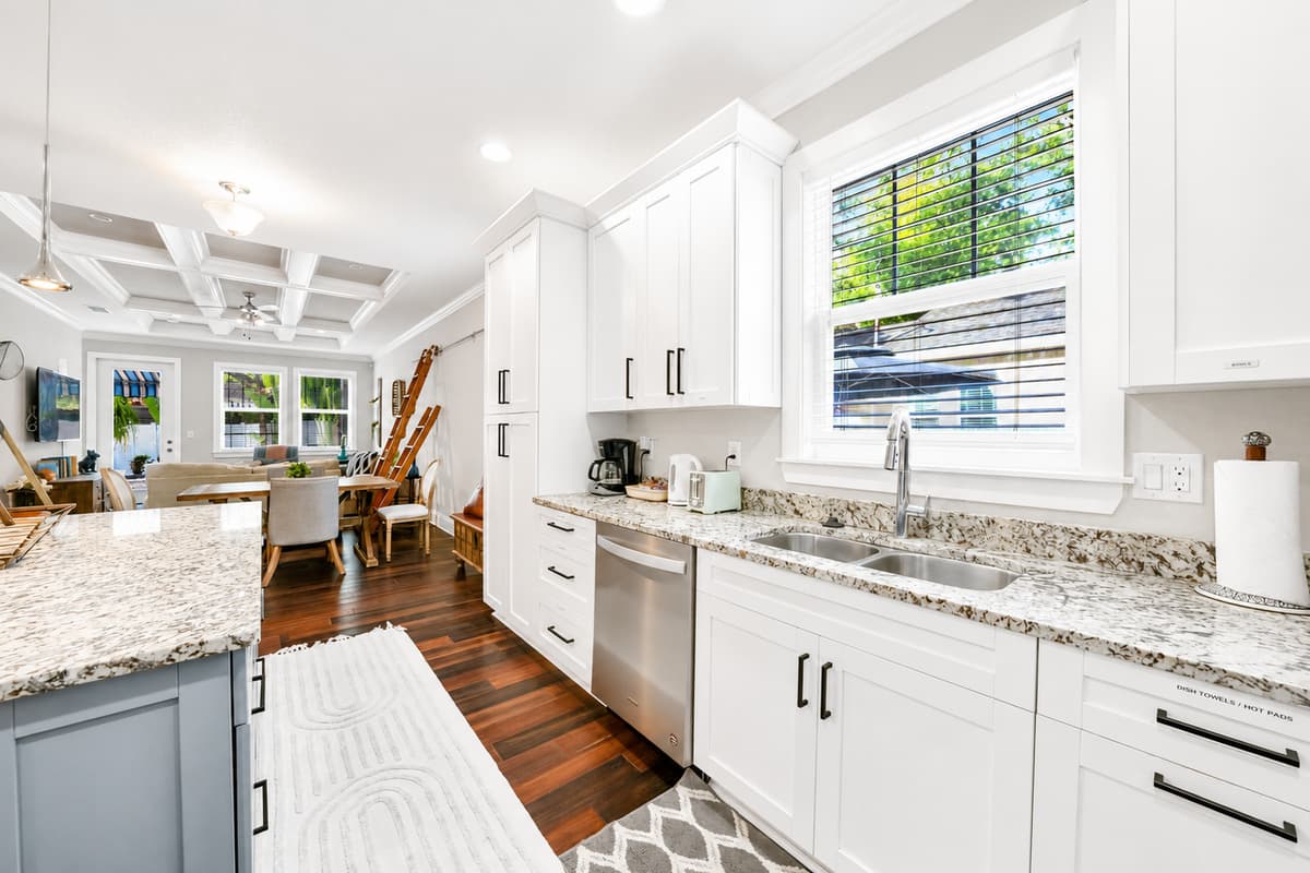 Bright windows fill the kitchen with natural light while offering plenty of prep space and modern finishes.