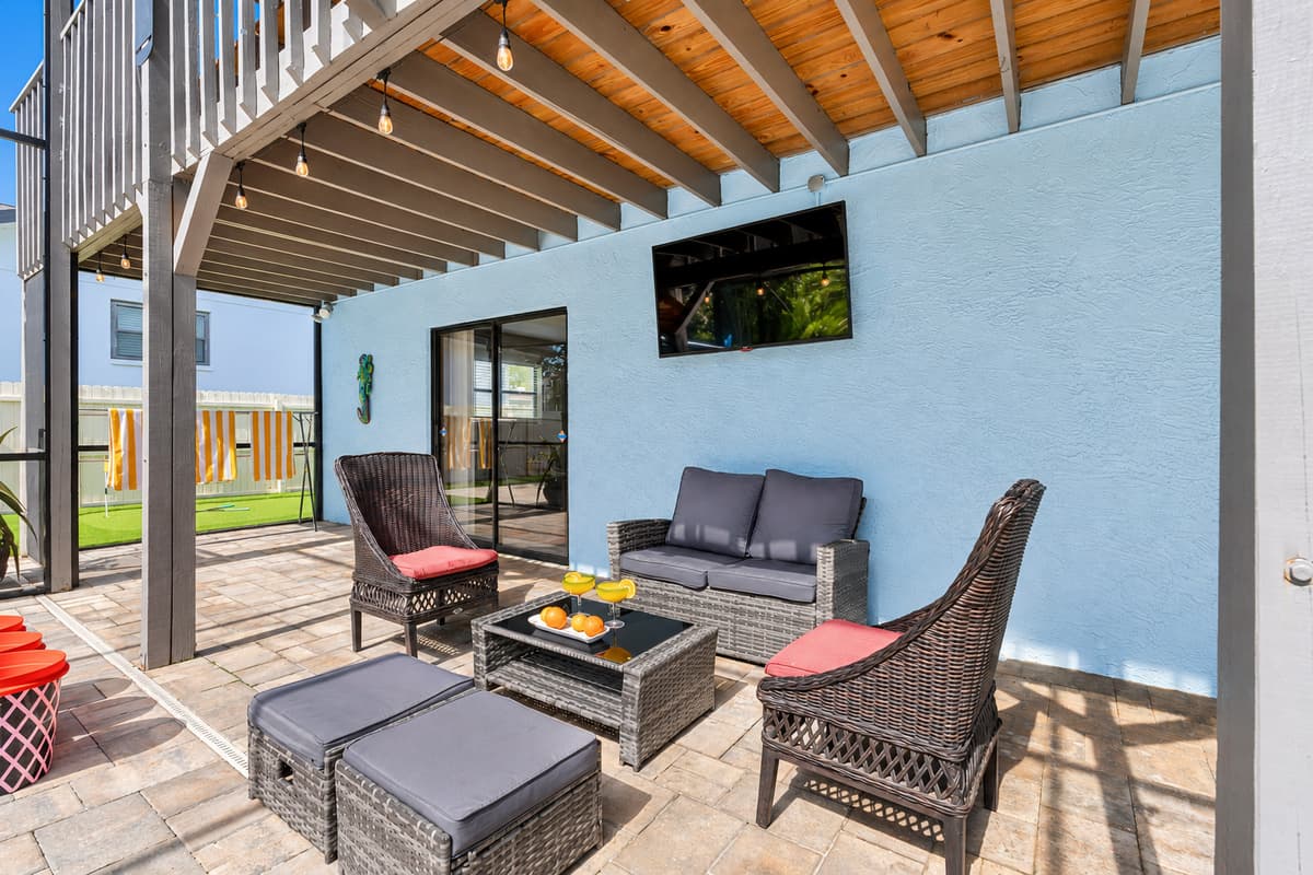 Unwind in the shaded sitting area with stylish rattan furniture, vibrant towels, and a view of the pool—perfect for your morning coffee or evening cocktails.