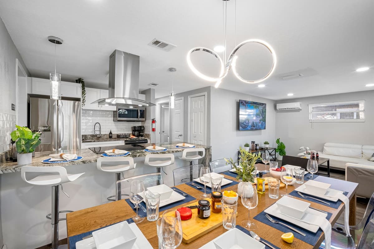 A stylish dining area featuring elegant table settings, modern lighting, and an open connection to the kitchen.