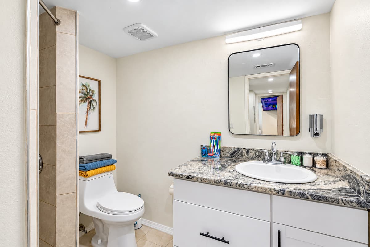 The sink is accompanied by a well-lit mirror, offering the ideal space for your morning routine or evening skincare rituals.
