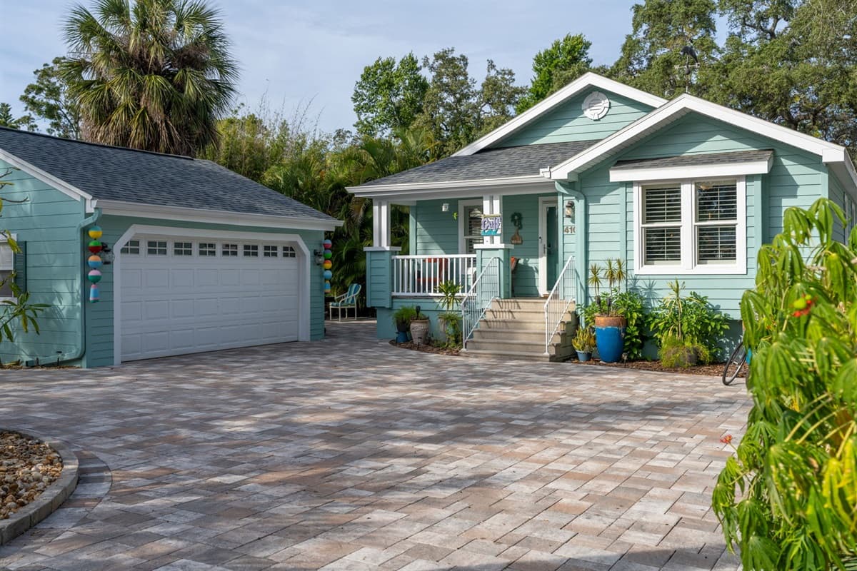 This charming coastal-style home features a mint-green exterior, inviting front porch, and beautifully landscaped entryway.