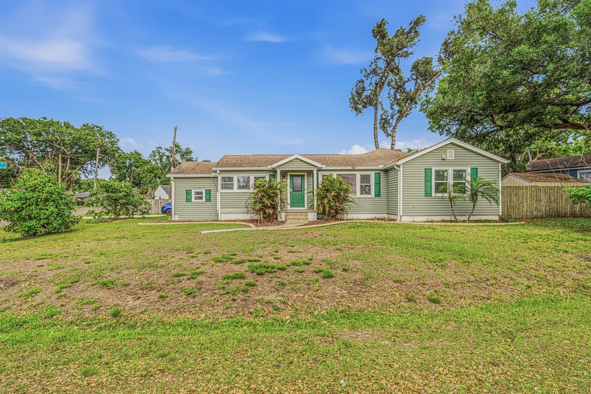 Wide view of the property showcasing large yard space and curb appeal in a quiet neighborhood.