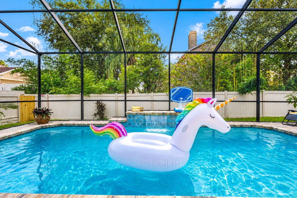 Dive into vacation mode in this serene, screened-in pool featuring a cascading waterfall and a playful atmosphere for guests of all ages.