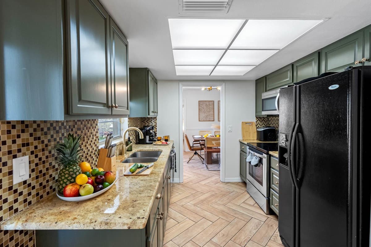 Whip up your favorite meals in this stylish kitchen featuring granite countertops, a sleek black fridge, and a mosaic tile backsplash for that designer touch.