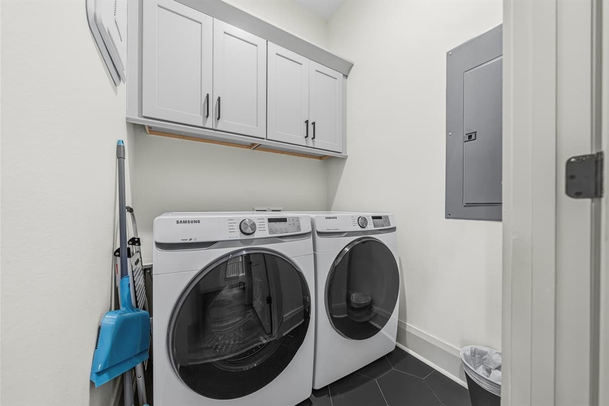 Brand-new in-unit laundry with front-loading washer and dryer, white shaker storage cabinets above, and a clean, bright layout. No laundromat runs needed — the convenience of home in the heart of Seminole Heights.