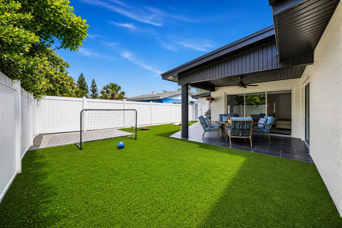 Spacious fenced backyard featuring a mini soccer goal and covered patio seating area.