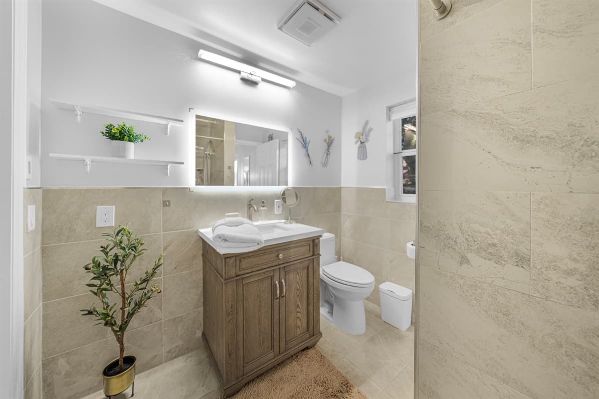 The bathroom feels luxurious and open, highlighted by a walk-in shower and stylish stone-inspired tile.