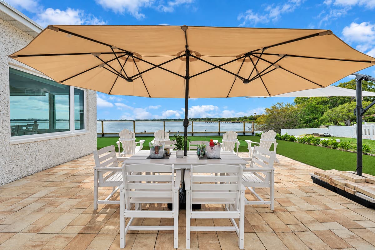 Shaded patio dining for the group. Two large umbrellas cover a long outdoor table with plenty of seats. Long lunches and late dinners in the fresh air.