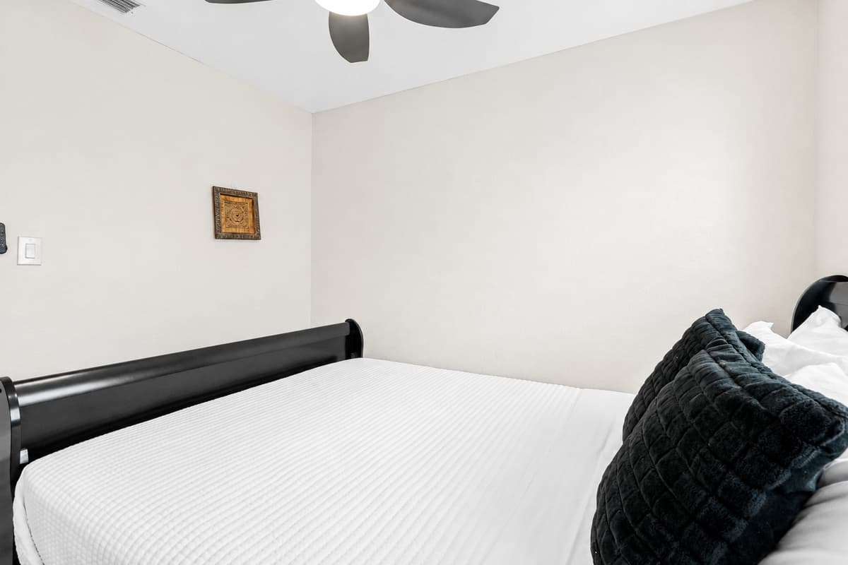 The full-size mattress is dressed in crisp white bedding, topped with two plush black accent pillows for a touch of texture and contrast.