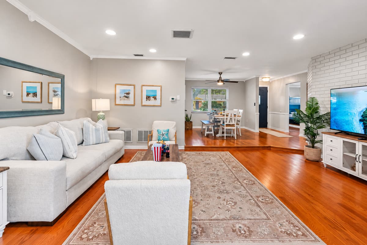 This light-filled living room offers plush seating, a large smart TV, and coastal-chic decor that sets the tone for a relaxing stay.