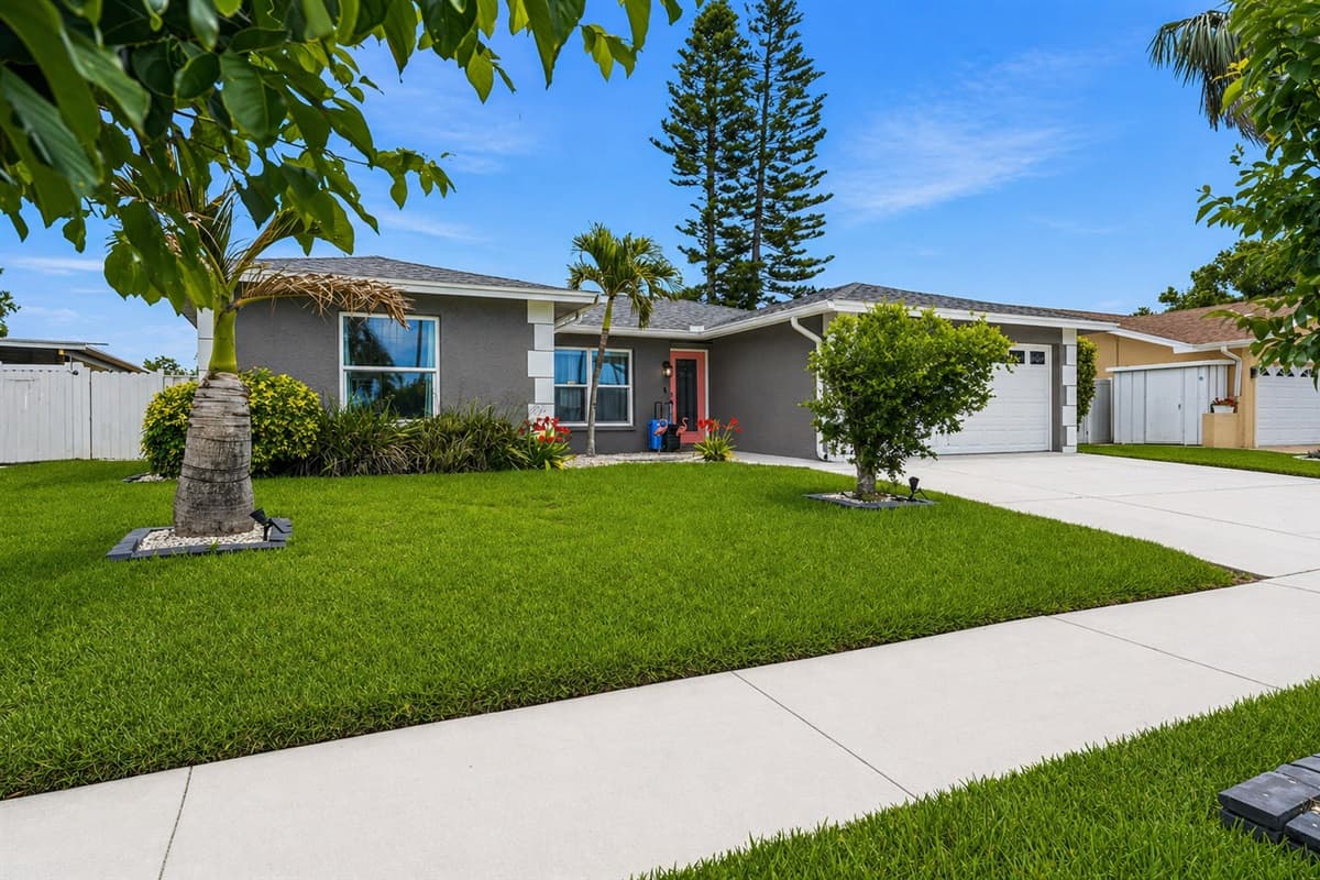 Wide front yard with manicured lawn and beautiful greenery.