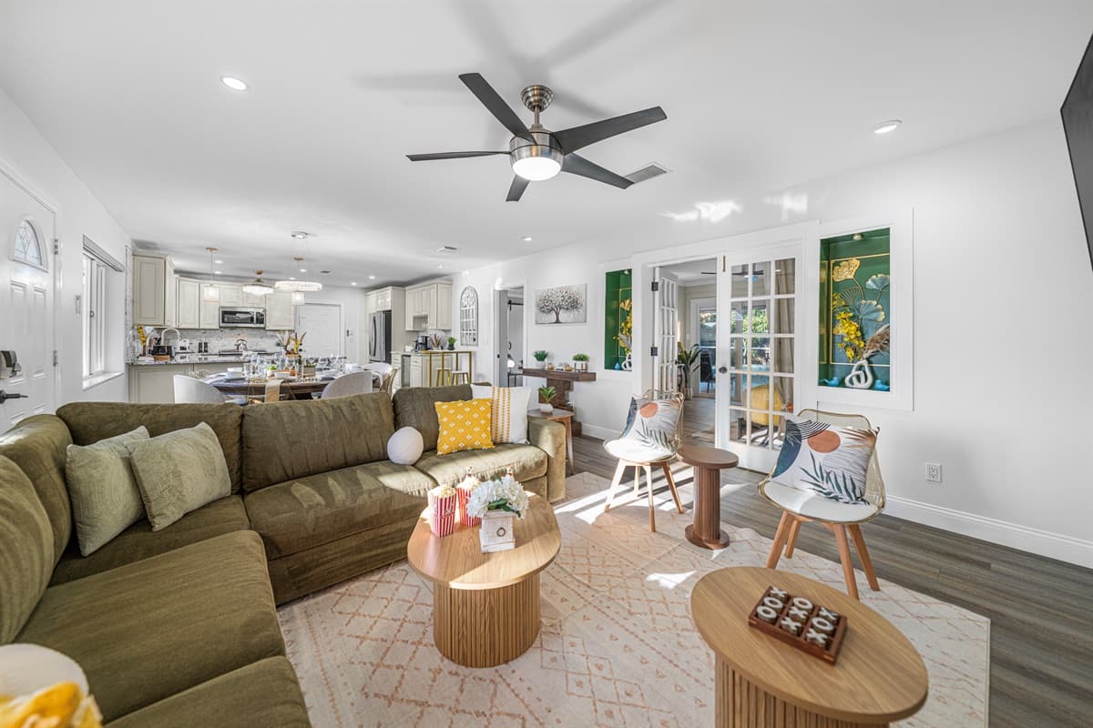An open-concept living area filled with natural light, featuring a large sectional, accent chairs, and a sleek entertainment setup for laid-back evenings.