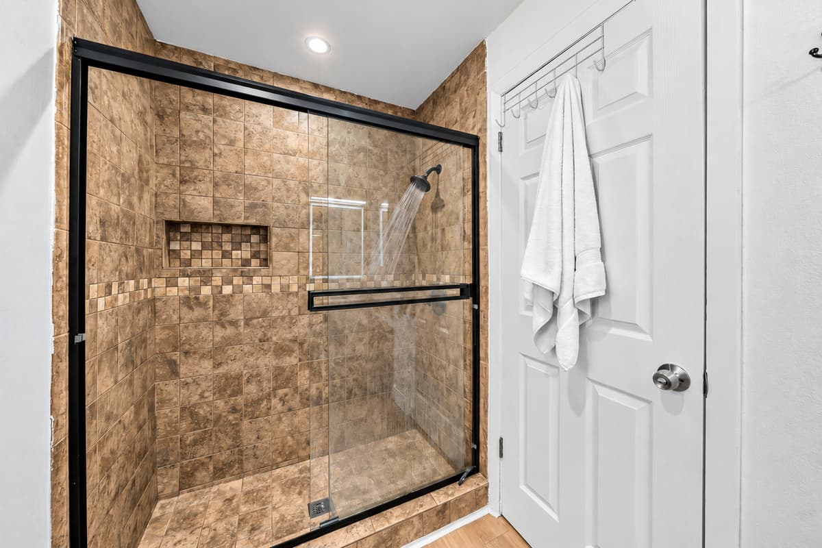 Glass shower doors, quality finishes, and a framed mirror elevate this space above the average rental bath.